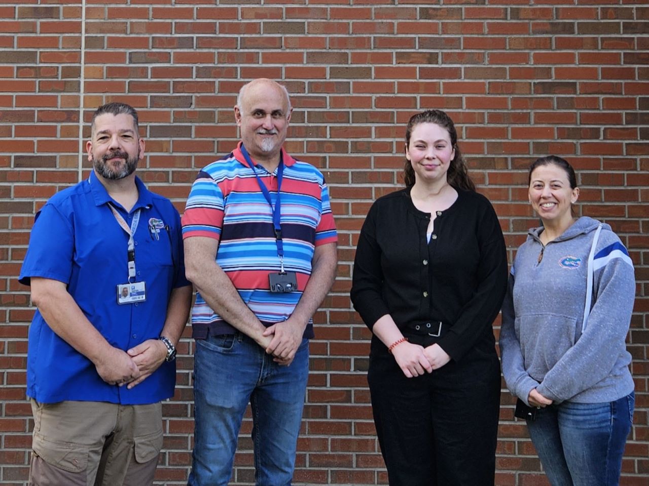 Four researchers stand against a brick wall facing the camera