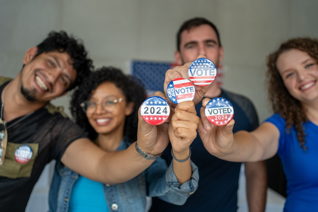 young people in group holding up Vote buttons