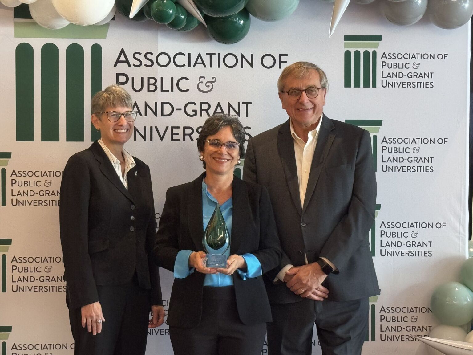 Three people pose with an award.