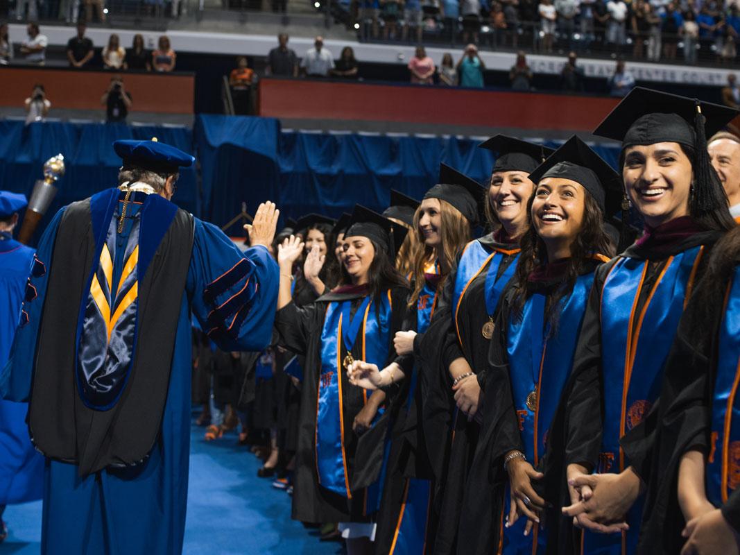 UF President Kent Fuchs high-fives students at a graduation ceremony.