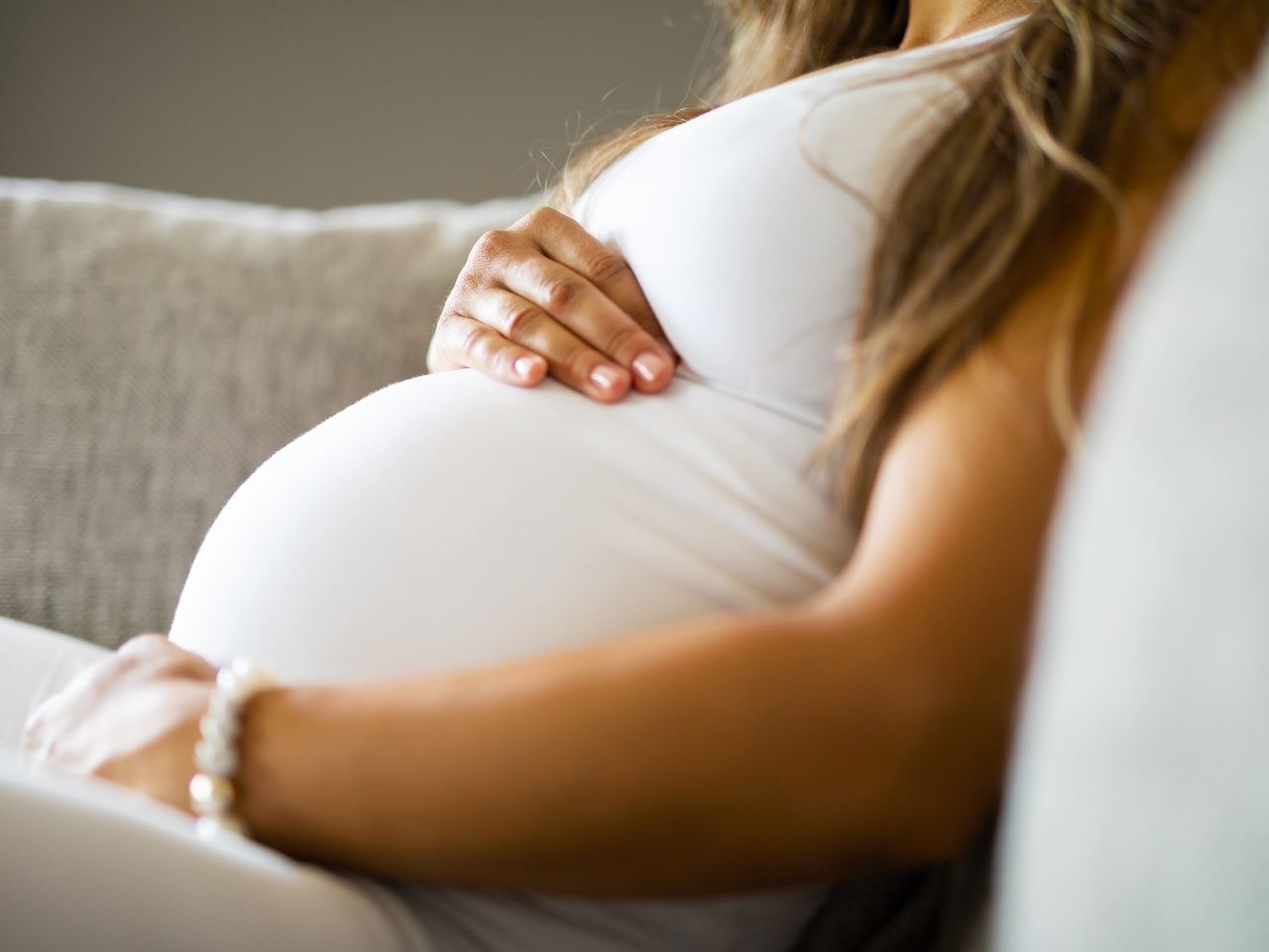 The torso of a pregnant woman cradling her stomach