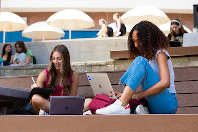 Two students sitting together in front of laptop.