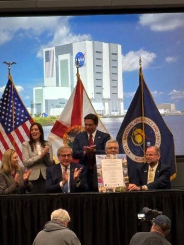 Ron DeSantis and UF administration signing a document outside of the Kennedy Space Center.