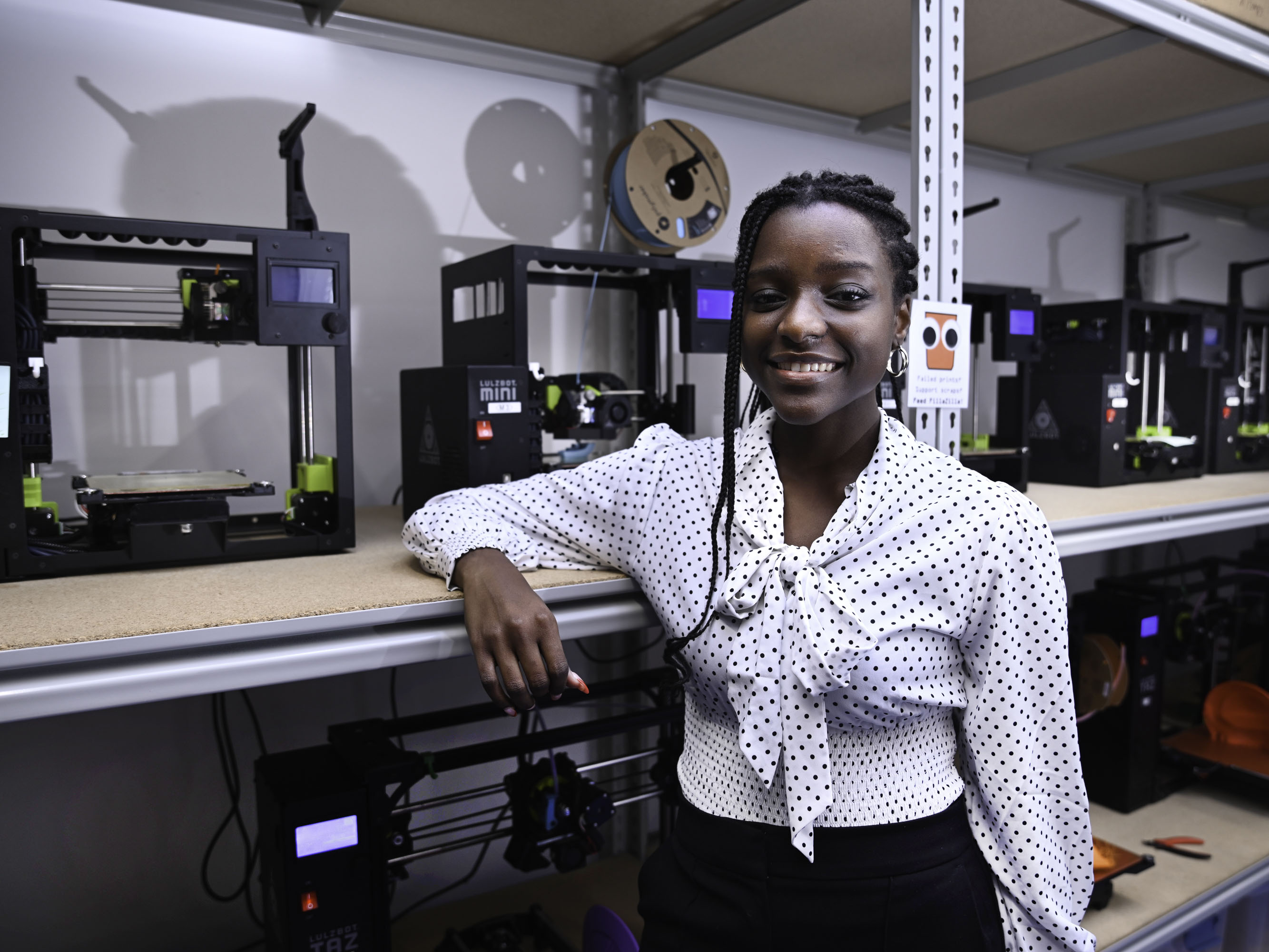 Rokheyatou “Roxie” Faye poses next to 3D printers in the Herbert Wertheim Laboratory for Engineering Excellence