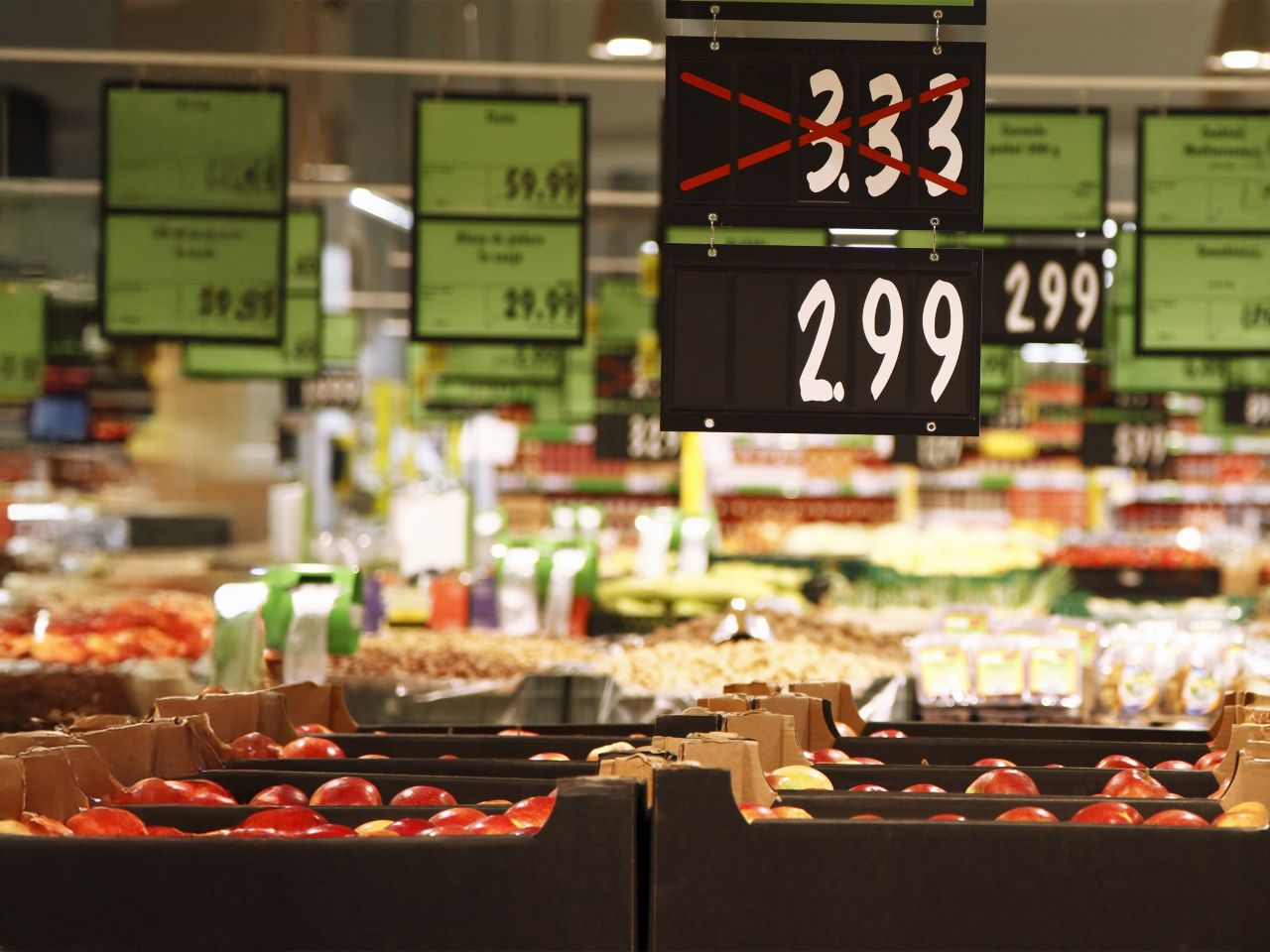 Inside a grocery store showing a crossed out price sign with a lower price below it