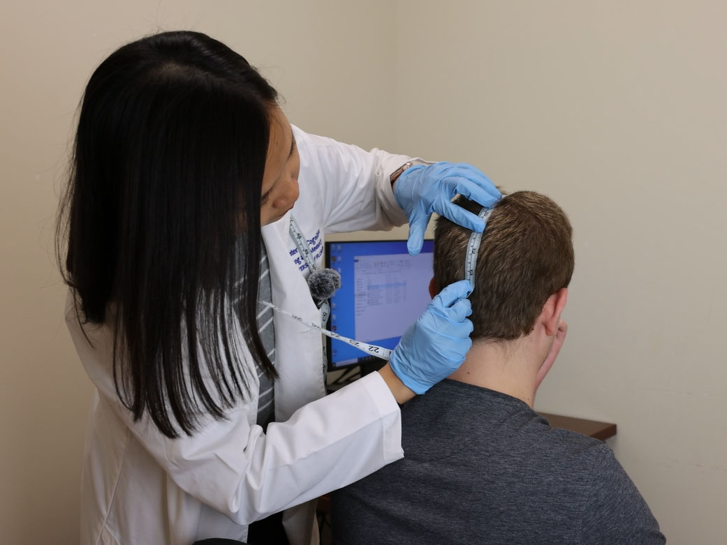 Dr. Queen demonstrates how she measures a participant’s head to determine the appropriate location to place transcranial direct current stimulation electrodes, following a standardized protocol.