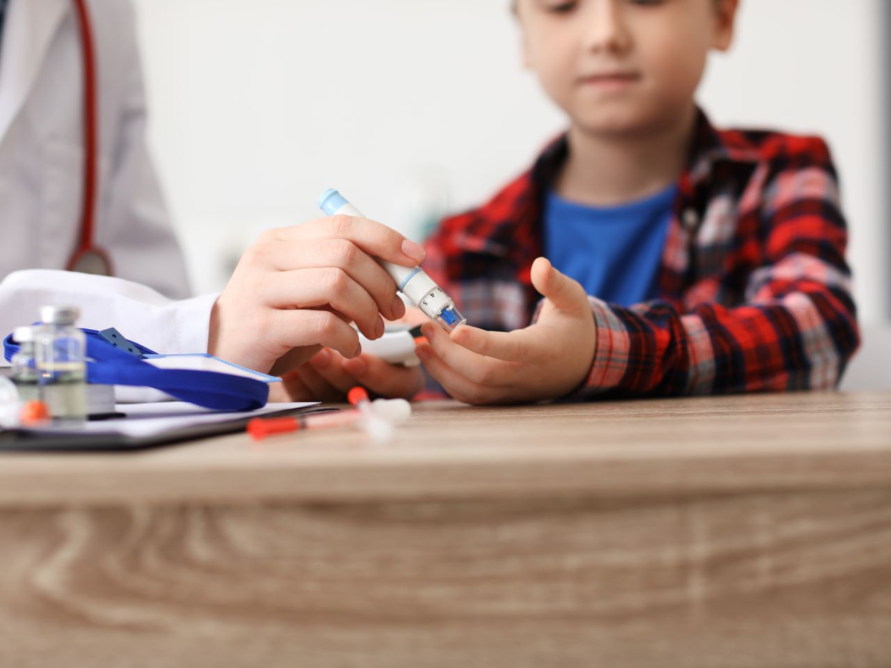 An adult helps a child provide a finger stick test for blood sugar