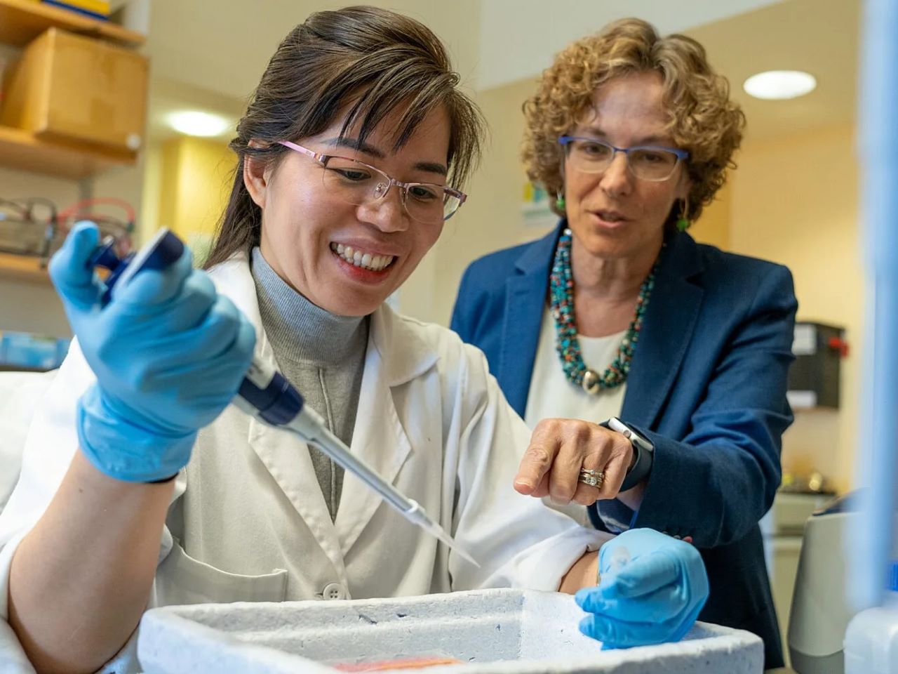 Two scientists gesture at a lab bench