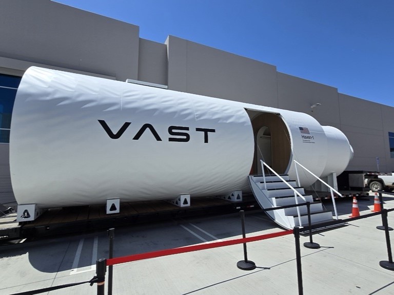A white, cylindrical research chamber with a door cut in the side and the letters 