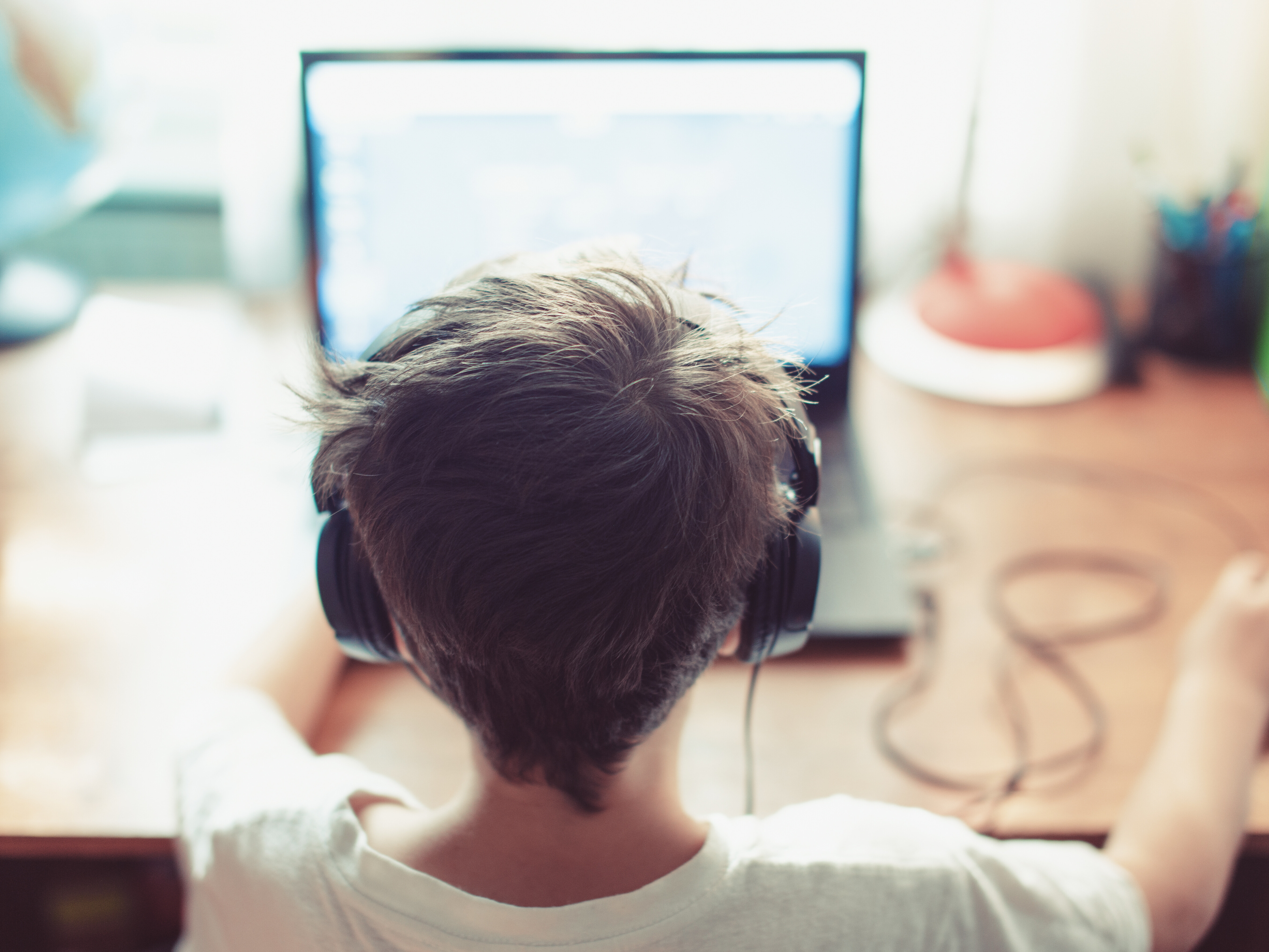 A child wearing headphones sitting in front of a computer screen