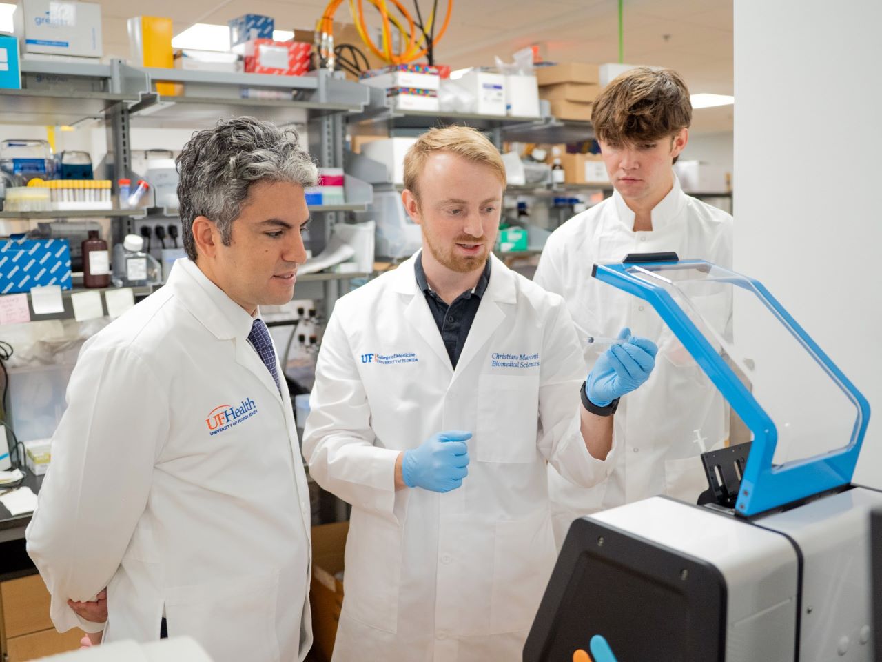 Three scientists in lab coats work in a lab
