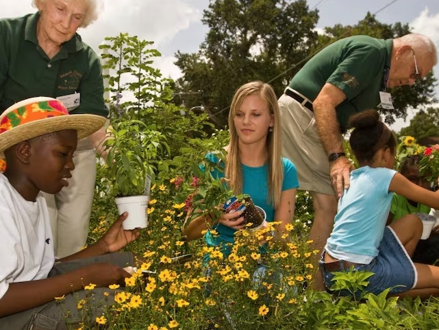 UF/IFAS Master Gardener volunteers work with students to plant flowers. [ UF/IFAS ]