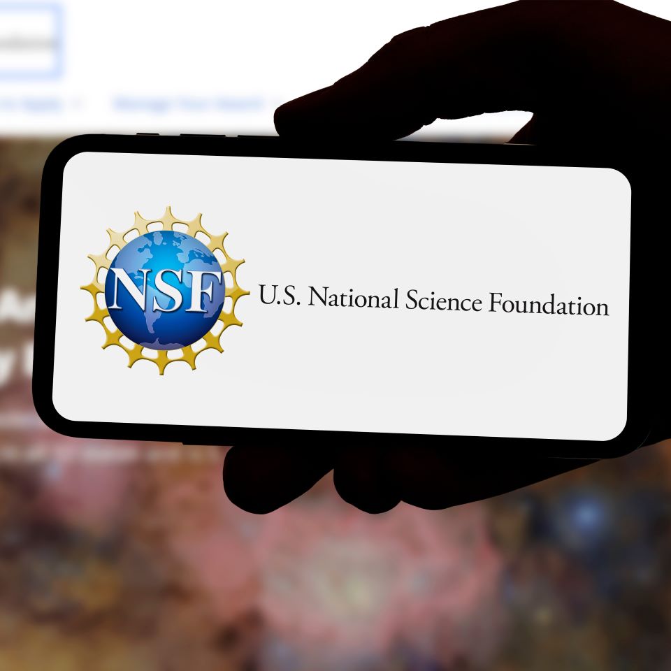 A hand holding up a phone with the logo of the National Science Foundation on it