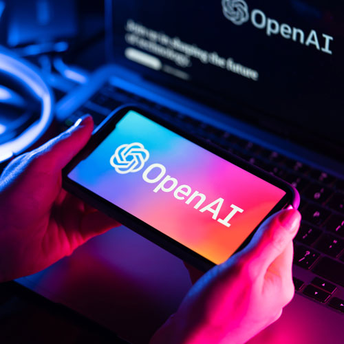 Hands holding a smart phone with the OpenAI logo on it.