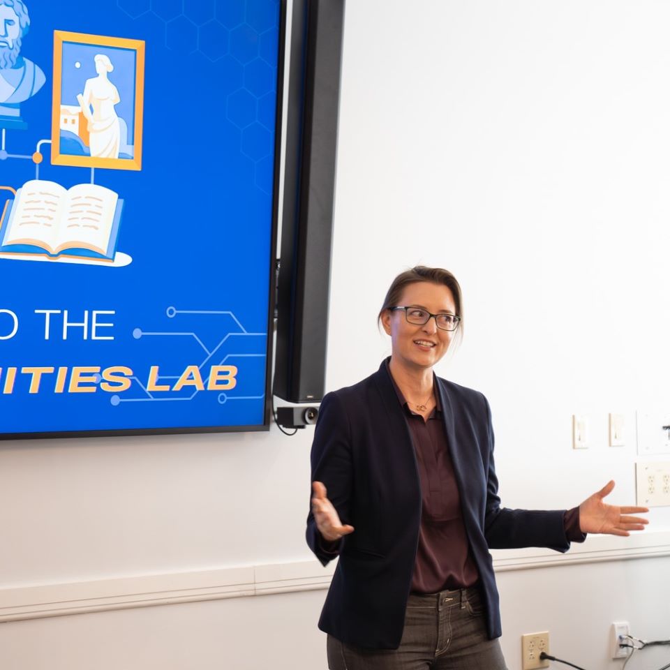 A woman standing in front of a screen saying 