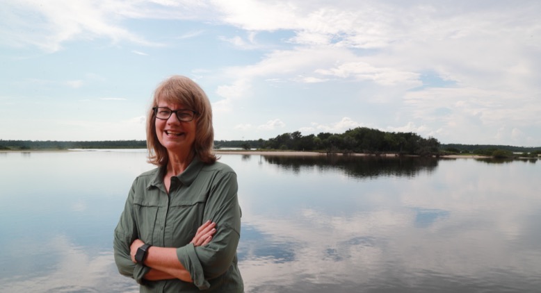 Environmental journalist Cynthia Barnett standing in front of a body of water.